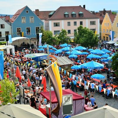 Bild vergrößern: Foto einer Menschenmenge auf dem Marktplatz beim Brgerfest 2015. Blaue Schirme und bunte Fahnen sind zu sehen.