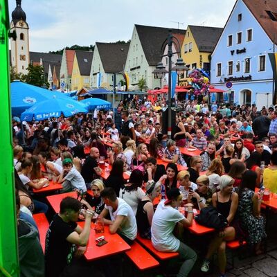 Bild vergrößern: Foto einer Menschenmenge auf dem Marktplatz beim Brgerfest 2015. Menschen sitzen auf roten Bierbnken.