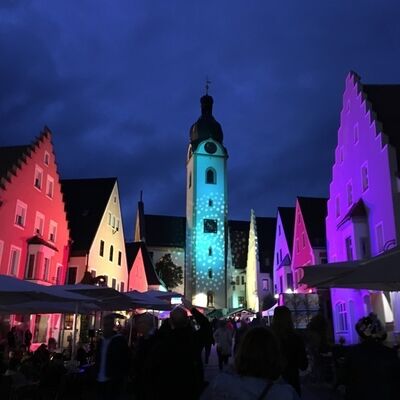 Bild vergrößern: Foto der Marktplatzhuser Schwandorf, die bei Nacht mit bunten Lichtern bestrahlt  werden.