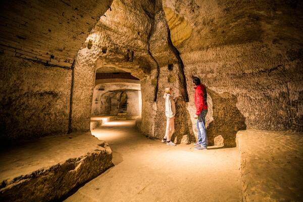 Zwei Besucher sehen sich im gut beleuchteten Felsenkeller eine Spalte in der Wand an.