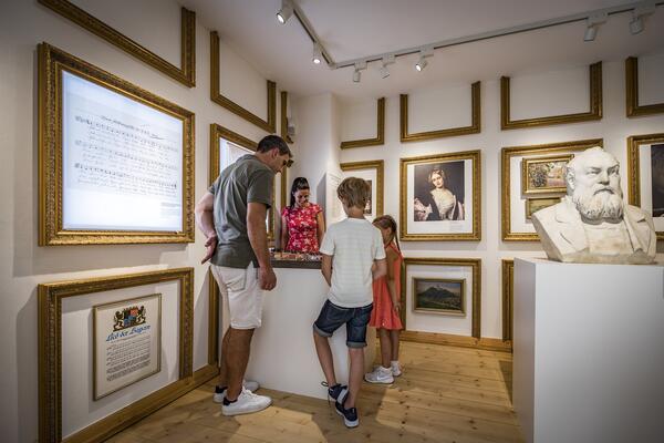 Eine Familie mit zwei Kindern betrachtet ein Objekt im Stadtmuseum. 