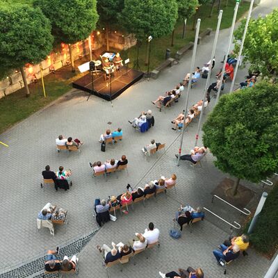 Foto: Vogelperspektive auf das Open-Air Veranstaltungsgelnde des Kultursommers 2020 im Hof vor dem Rathaus Schwandorf. Zahlreiche Besucher:innen sitzen vor der erleuchteten Open-Air-Bhne.