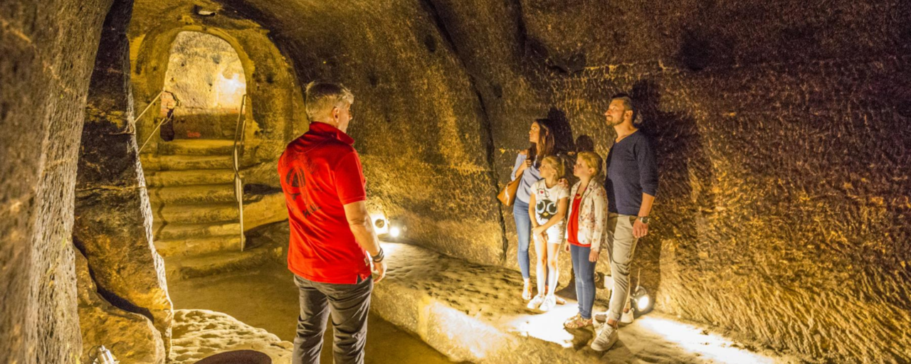 Bild vergrößern: Ein Fhrer und eine Familie im gut beleuchteten Felsenkeller
